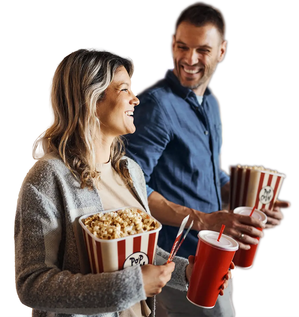 Man and woman carrying popcorn and soda in a movie theater