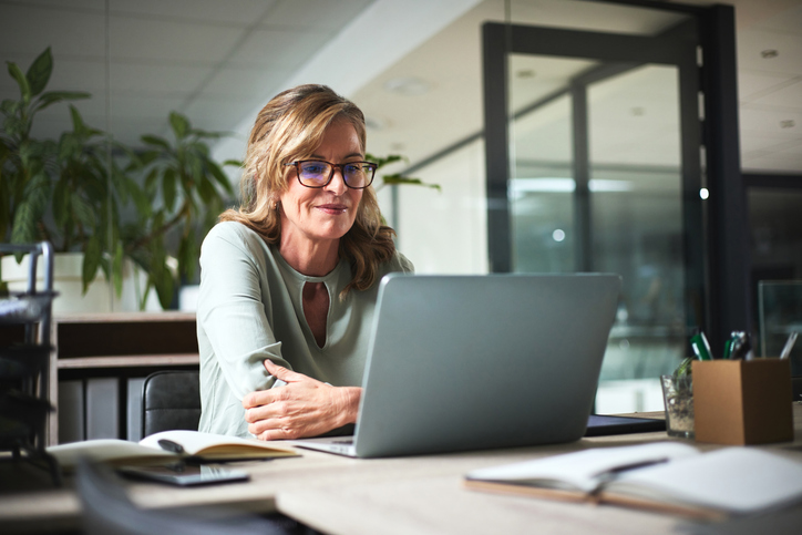 Older professional working on laptop in her office