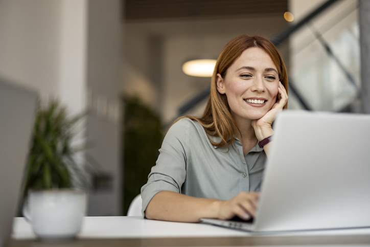 Smiling Woman Working Remotely on Laptop in Modern Workspace