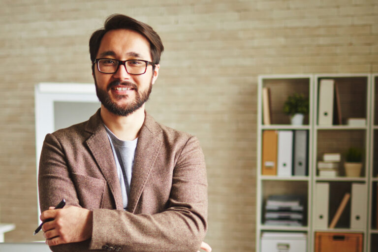 Man smiling with arms crossed standing in room