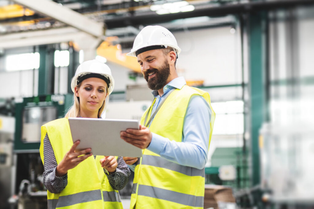 Man and woman standing in a factory looking at a tablet