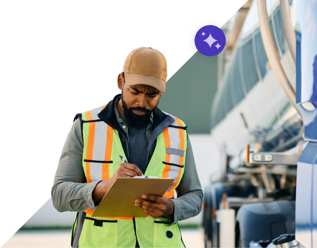 man wearing construction vest looking at and writing on clipboard in hands