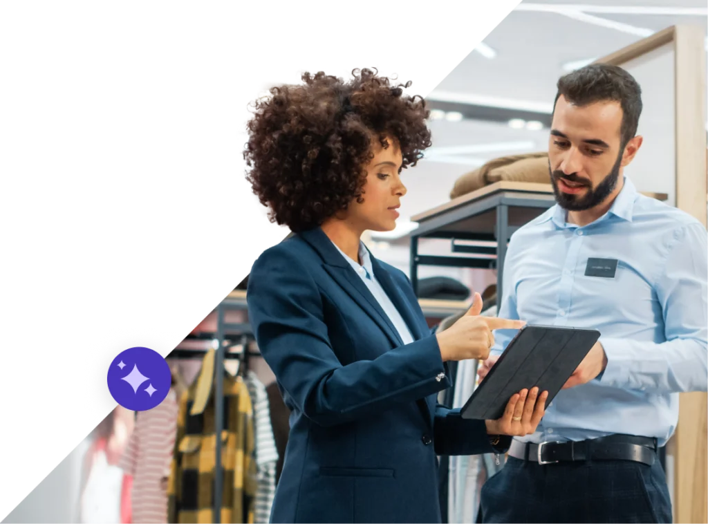 Frau hält Tablet mit Blick auf den Bildschirm, während sie mit dem Mann im Bekleidungsgeschäft darüber diskutiert