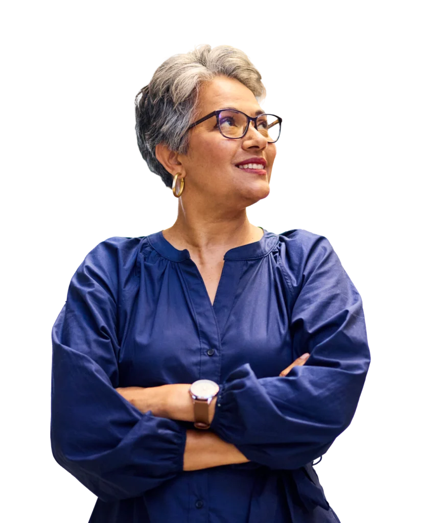 A woman looks to her left while smiling with her arms crossed