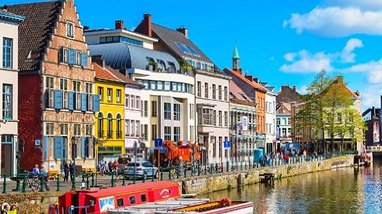Buildings overlooking the water, with pedestrians, cars, and boats in view