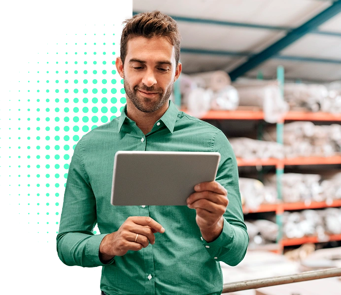 Man in green button up holding tablet in industrial setting