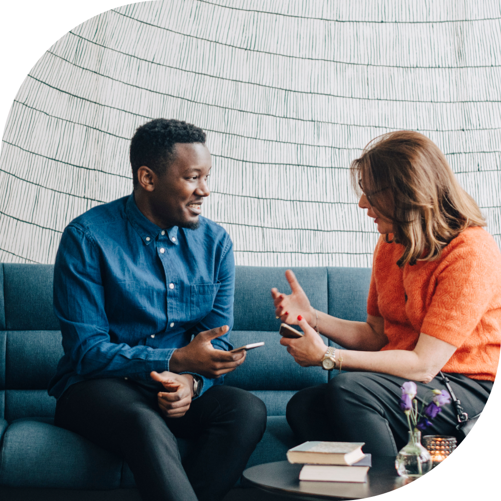 Two people sit on a couch holding phones, deep in conversation