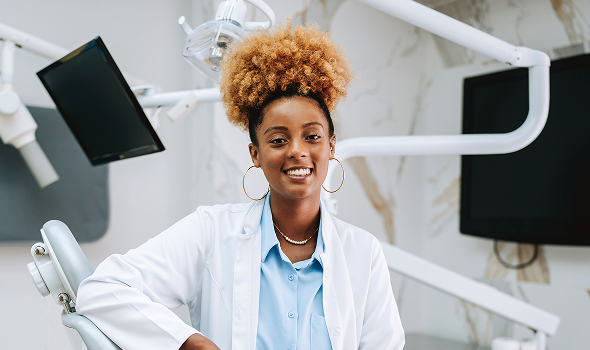 A worker in a lab coat in front of dental equipment