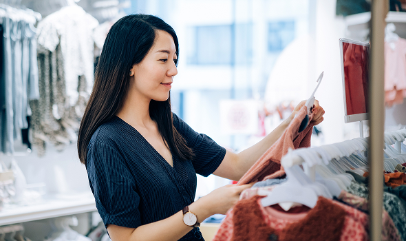 A person holds an item of clothing at a clothing store
