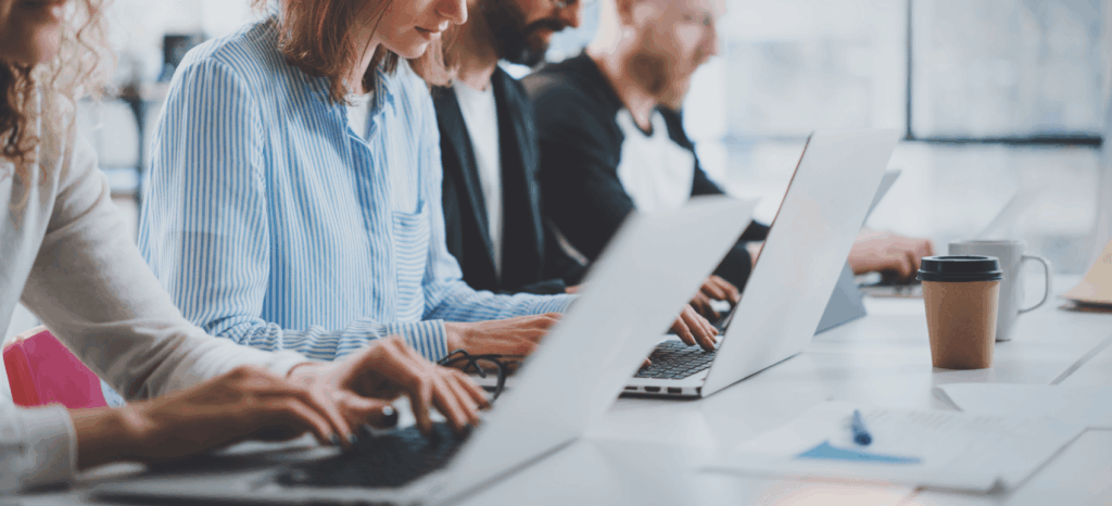 4 versteckte Kosten für Debitorenbuchhaltung technology_employees in einem Büro, das in einer Reihe sitzt und an seinen Laptops arbeitet