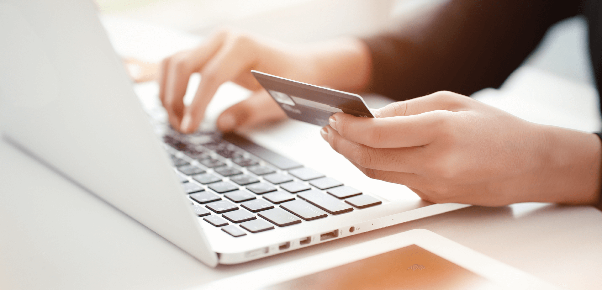 Closeup view of person holding a credit card while typing on a laptop