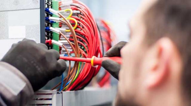 Electrician with gloves working on a box of wires
