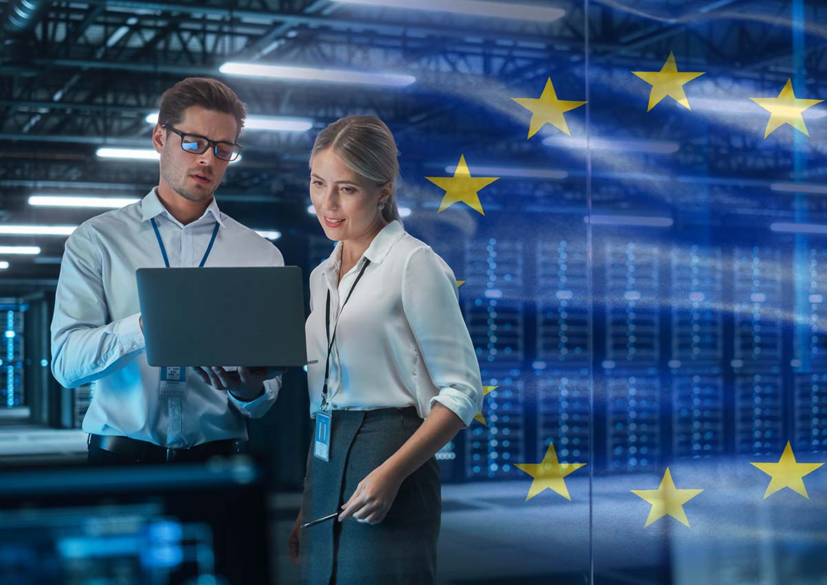 Two people working in data center with EU flag in background