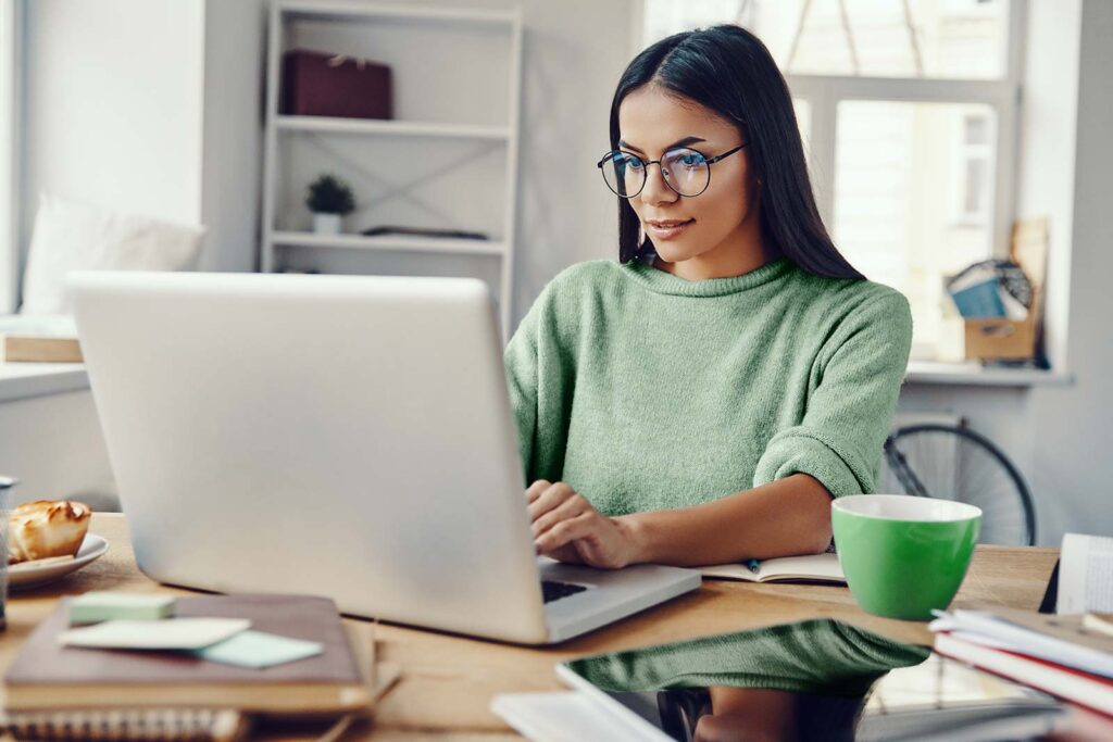 A woman smiling while working on a laptop
