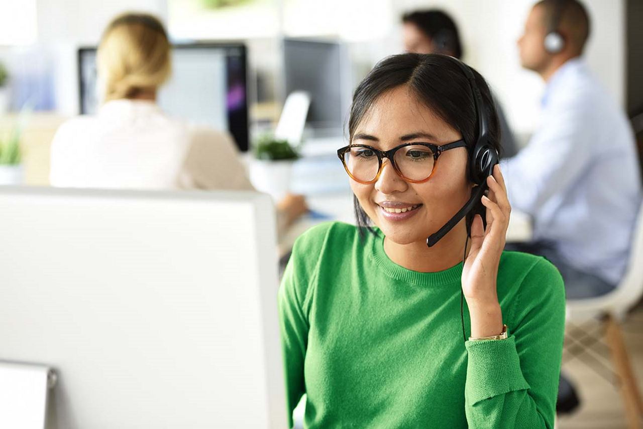 A woman on a work call smiles while looking at a computer screen