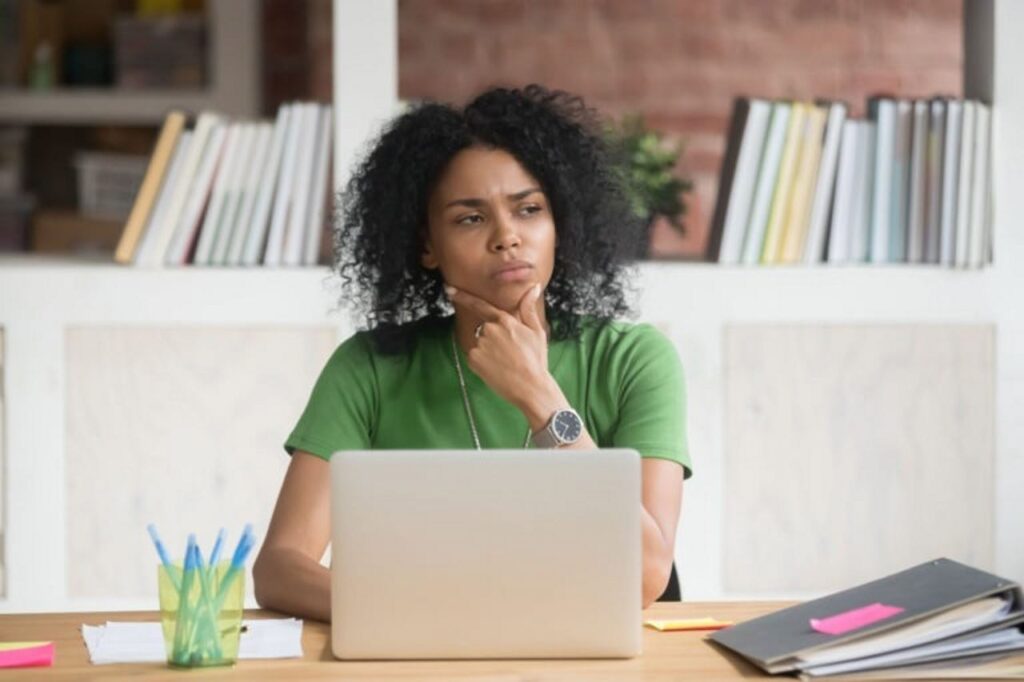A woman thinking at a desk with a laptop computer