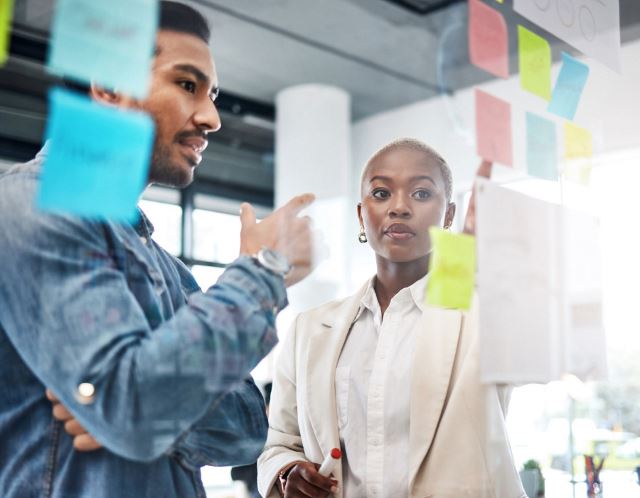 Coworkers strategizing over post-it notes