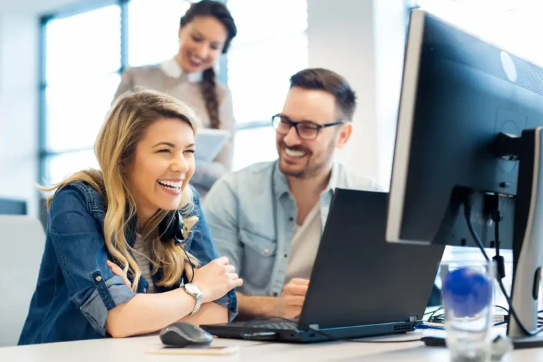 accounts receivable team smiling in front of laptop