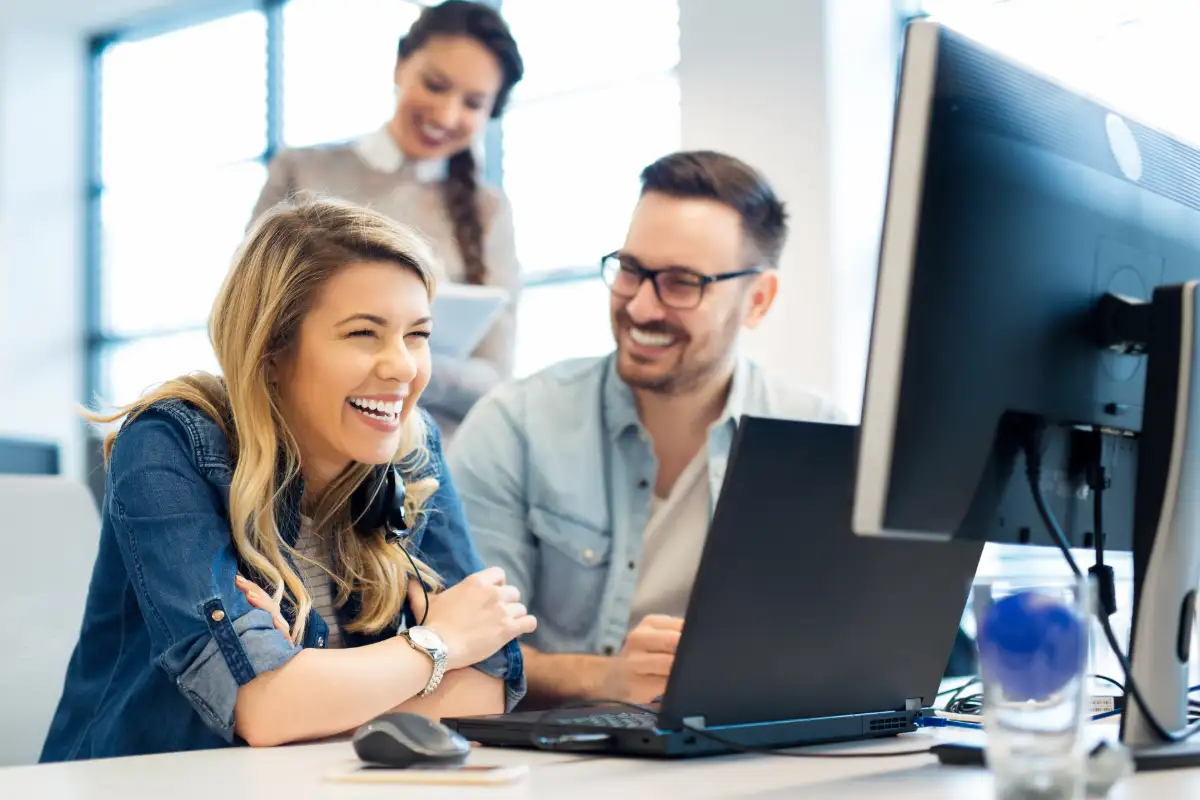 accounts receivable team smiling in front of laptop