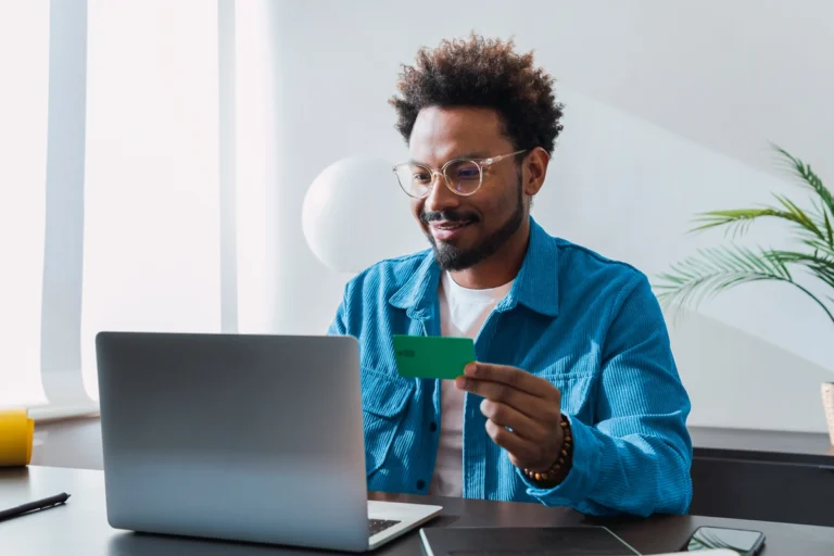 Man holding credit card and smiling with laptop