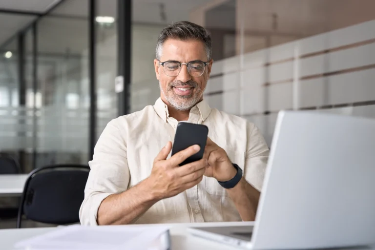 Man looking at phone reading Billtrust blog: Suppliers can’t avoid payment processing costs, but they can control them