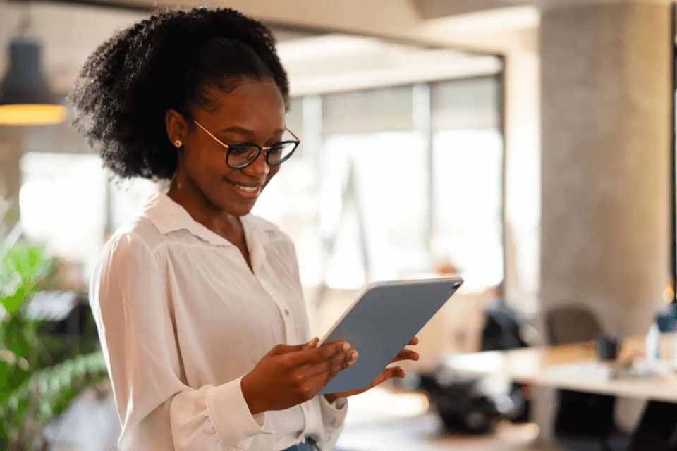 Women wearing glasses in a white short holding a tablet in office