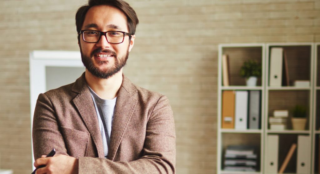 Man smiling with arms crossed standing in room