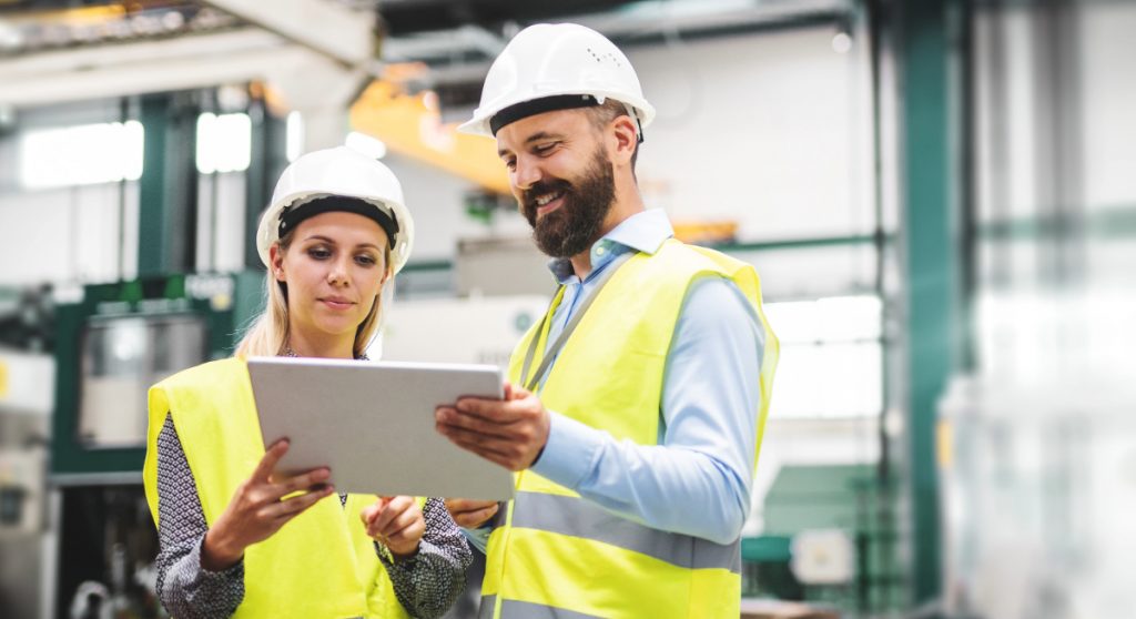 Man and woman standing in a factory looking at a tablet
