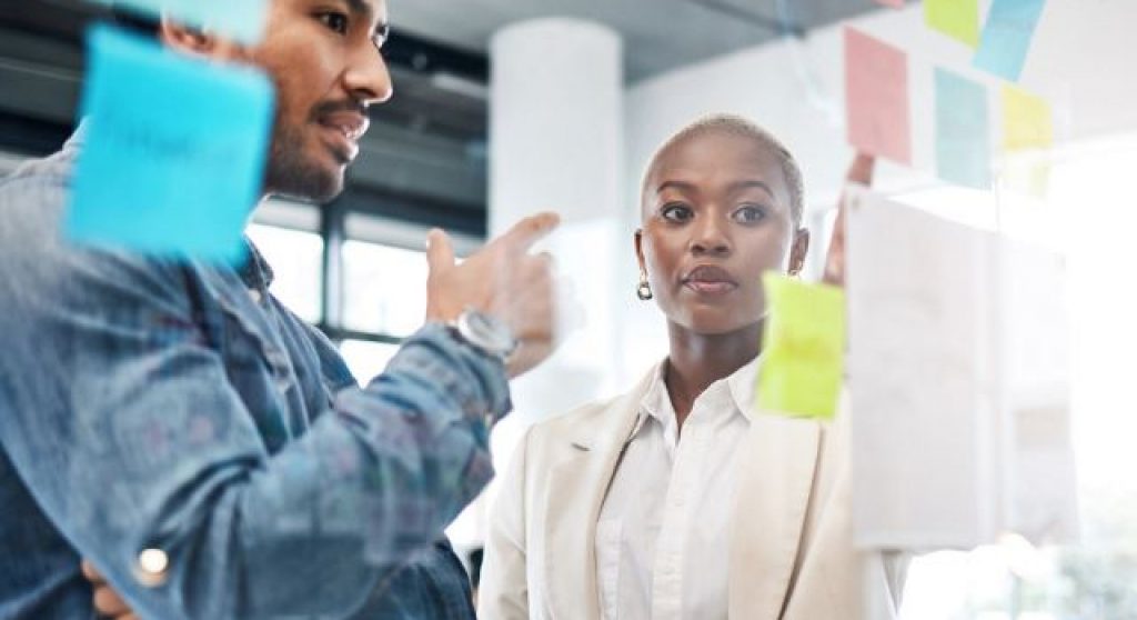 Coworkers strategizing over post-it notes