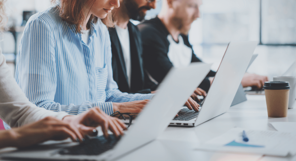 4 versteckte Kosten für Debitorenbuchhaltung technology_employees in einem Büro, das in einer Reihe sitzt und an seinen Laptops arbeitet