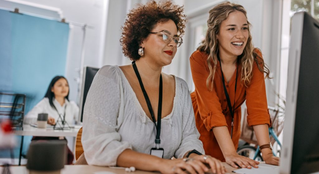 Two business colleagues working together on desktop computer at office