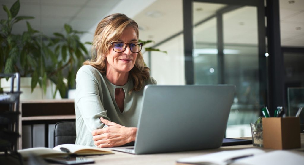 Older professional working on laptop in her office