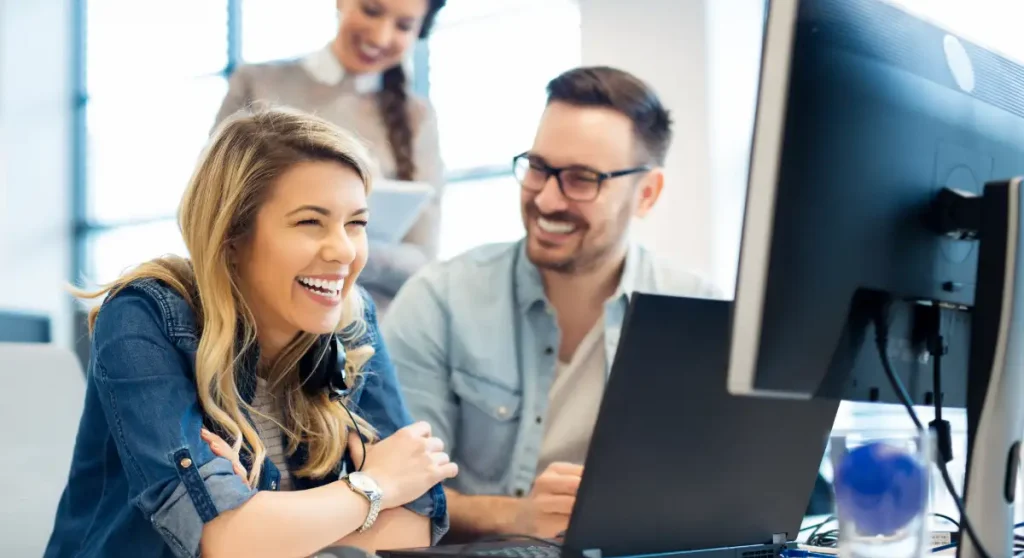 accounts receivable team smiling in front of laptop