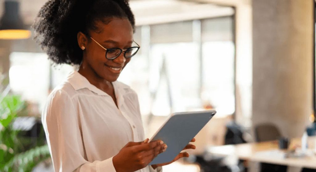Women wearing glasses in a white short holding a tablet in office
