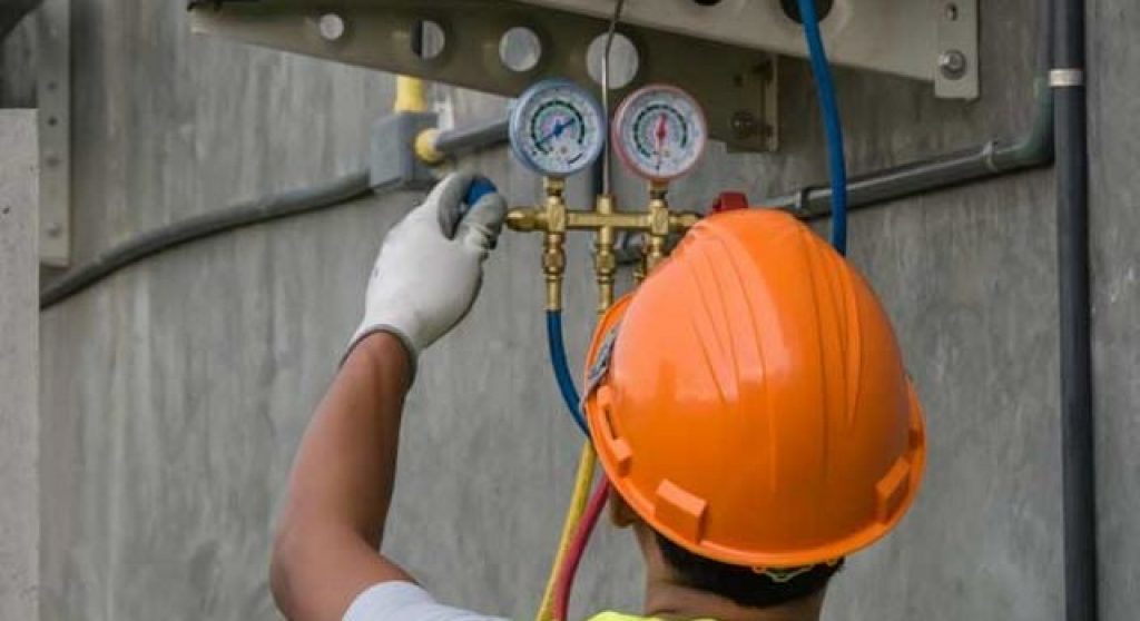 man in hardhat adjusting pressure gauge