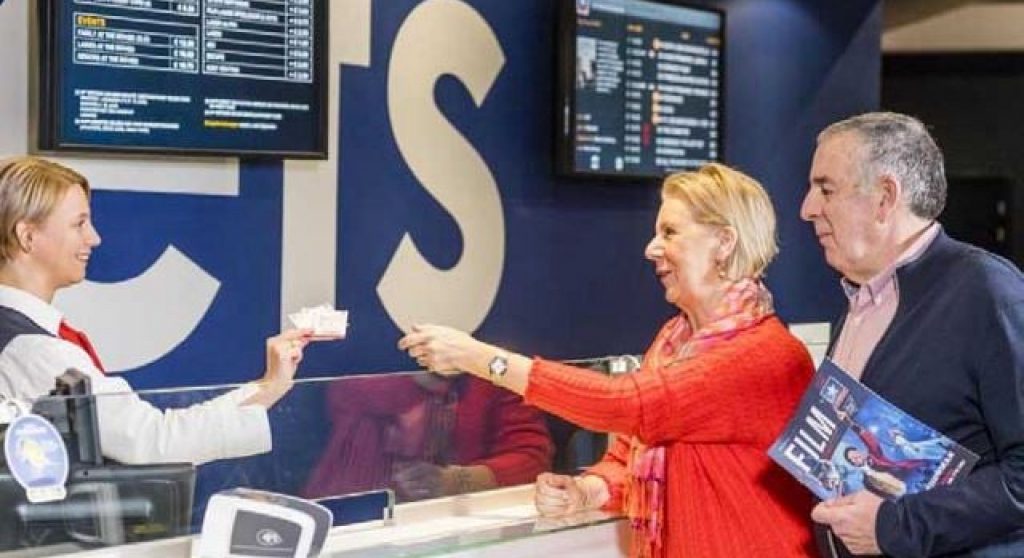 A couple getting tickets from a ticket agent