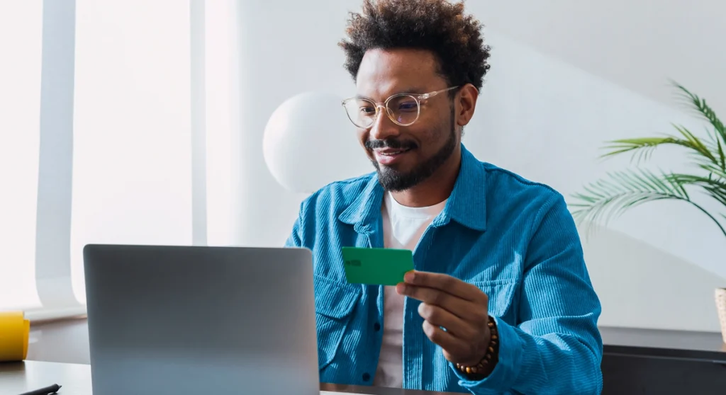 Man holding credit card and smiling with laptop