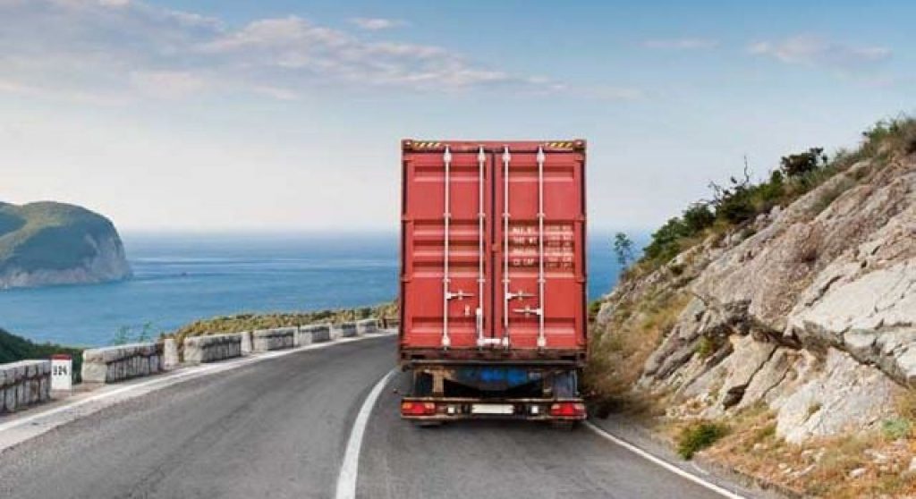 semi truck driving on a road by the ocean