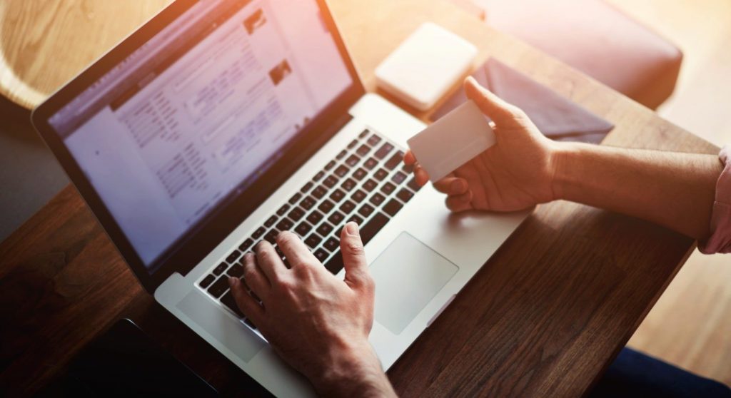 person paying bill on laptop holding credit card