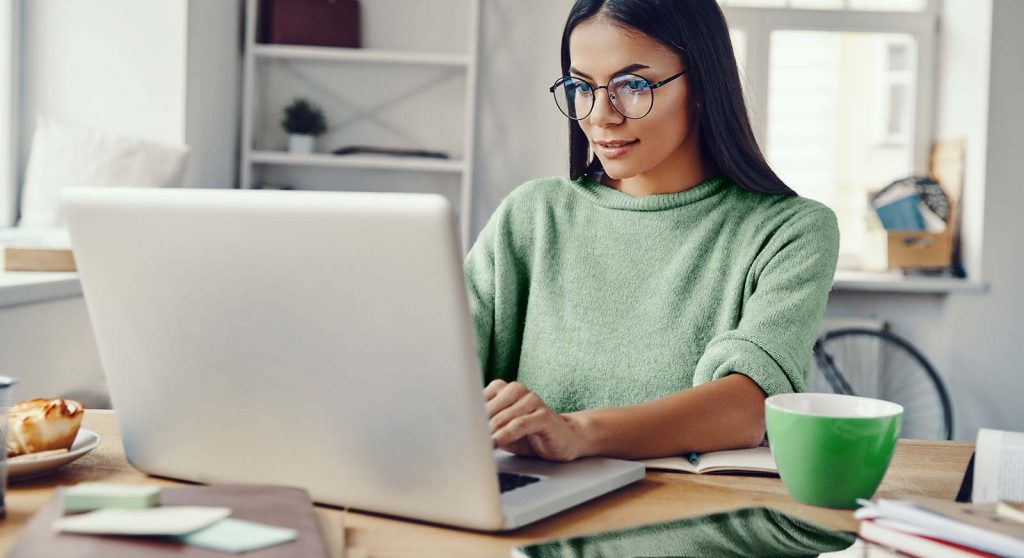 A woman smiling while working on a laptop