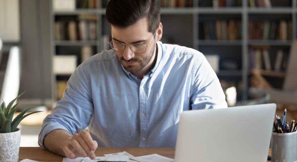 Professional using a calculator and laptop