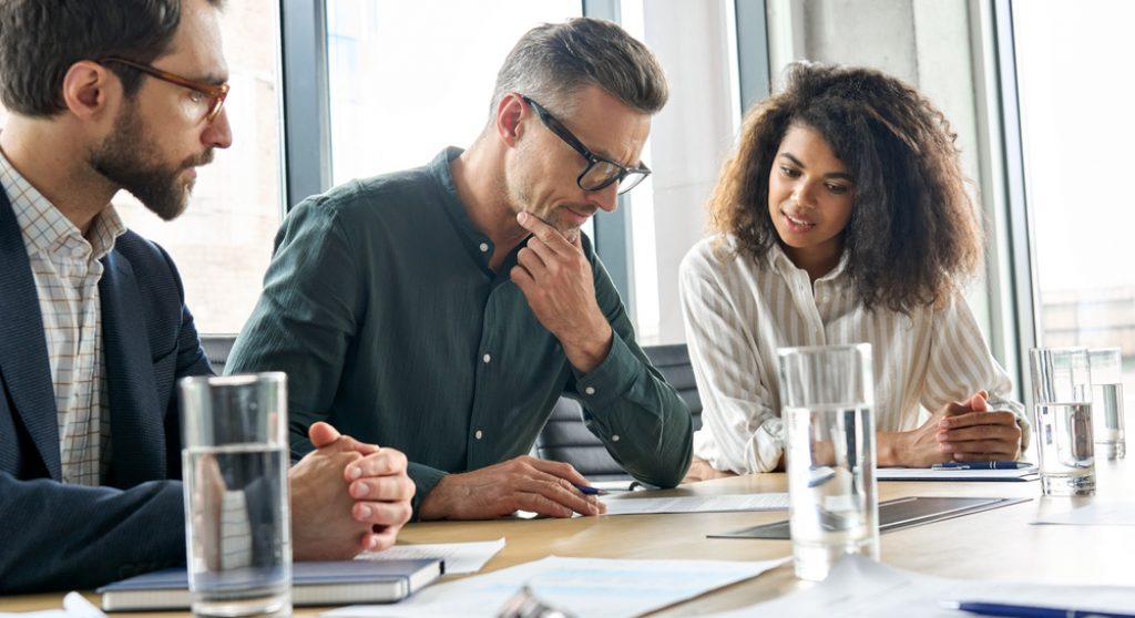 Focused mature businessman with two younger colleagues