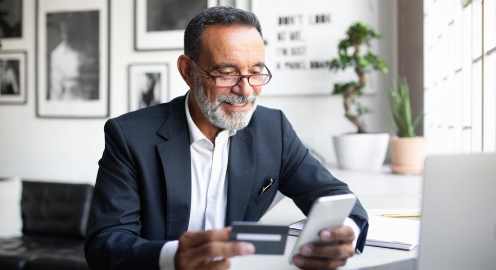 Older professional man paying with credit card on mobile device