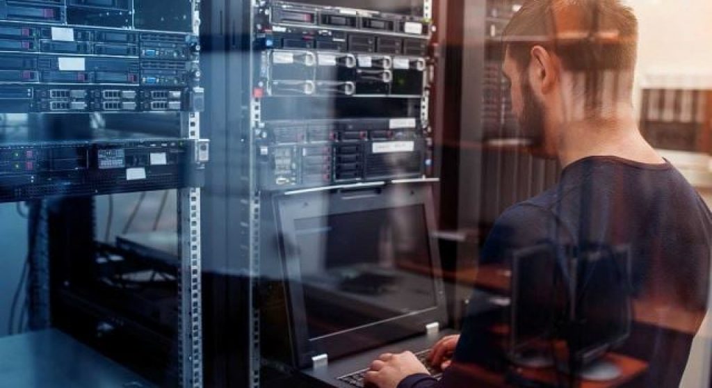 IT worker at a laptop in a server room