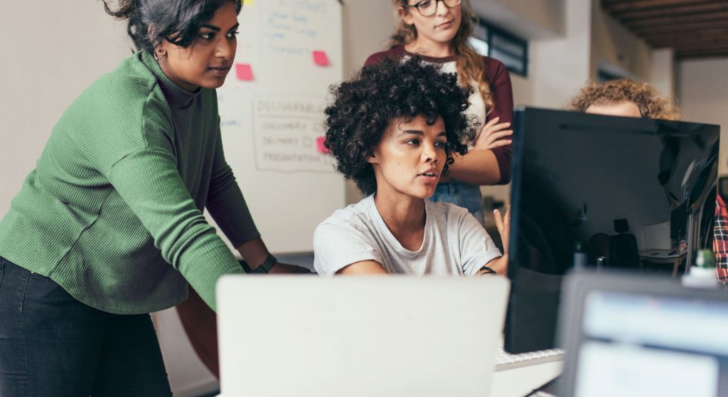 employees viewing a co-worker's computer screen in her office