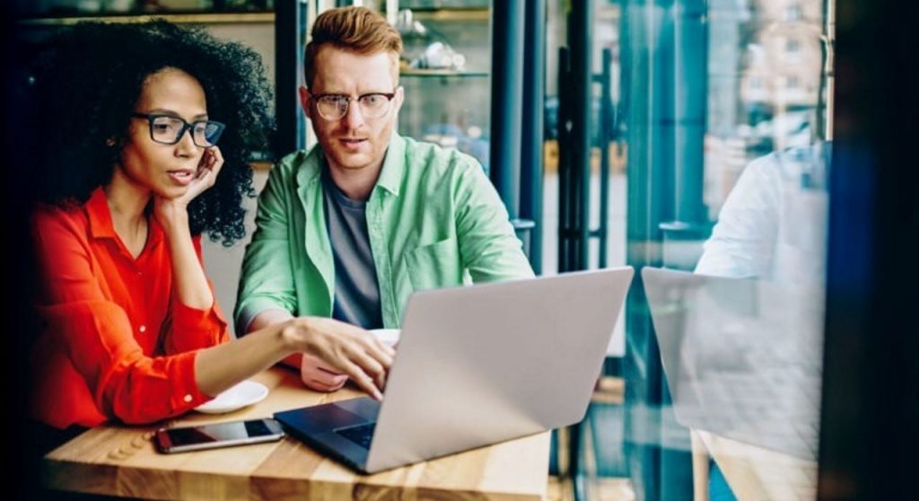 woman and man looking at a laptop screen in an office setting
