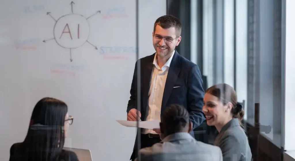 young professional talking to colleagues in front of whiteboard saying AI